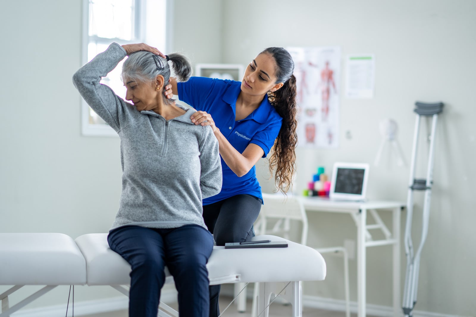 Therapist supporting an older patient through functional movement